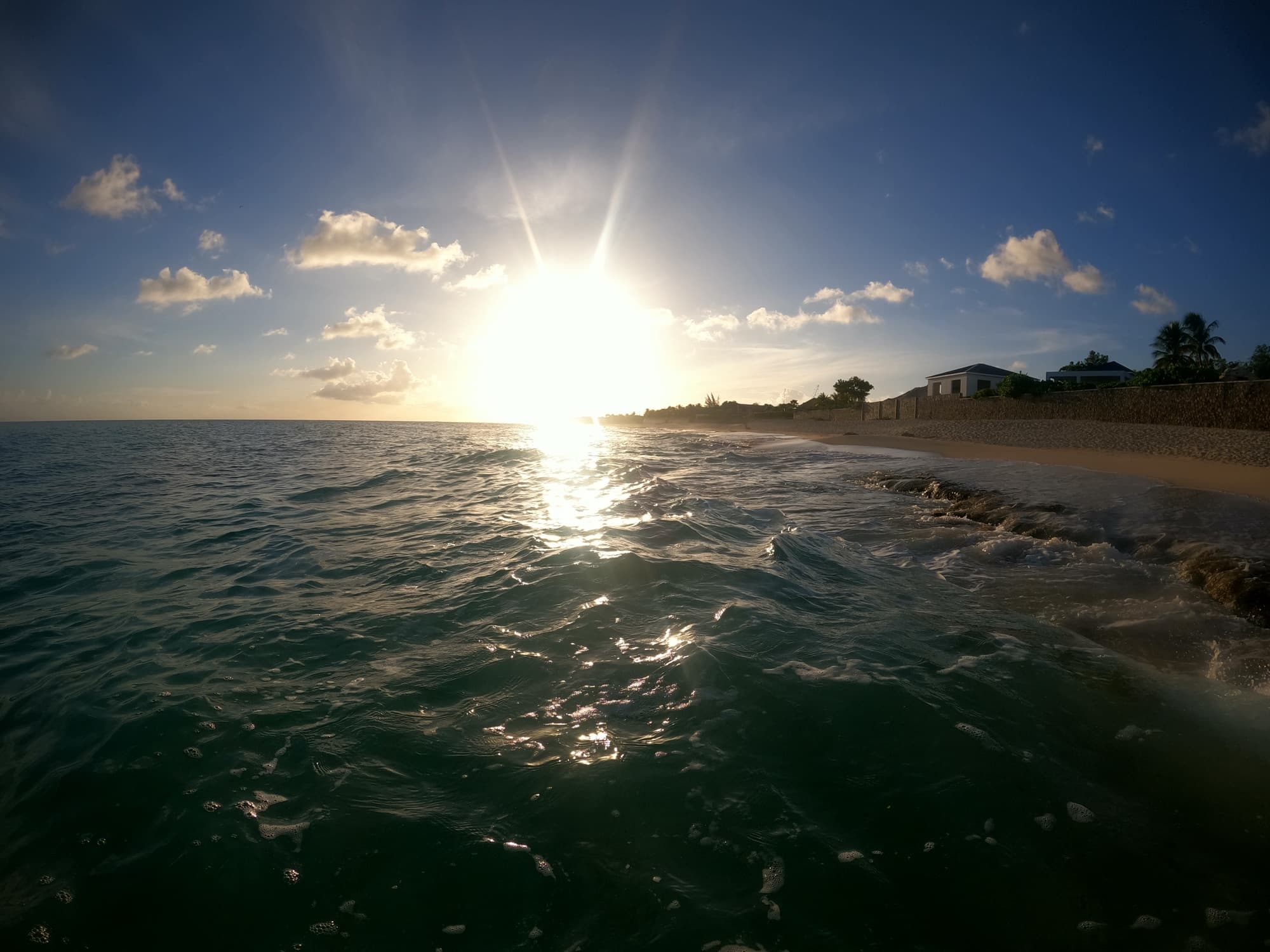 Golden hour sun sparkling on the water along Baie Longue beach