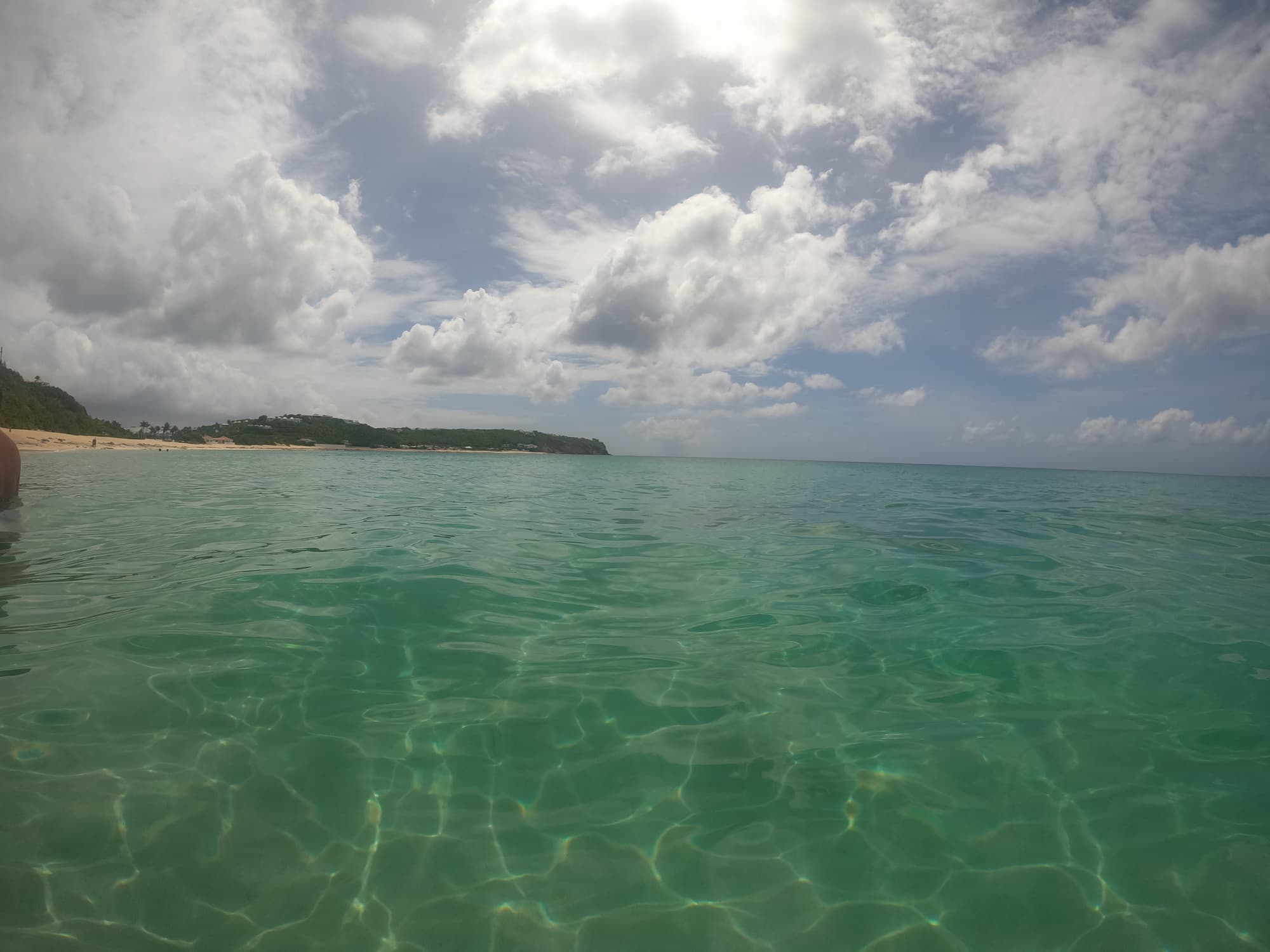 Crystal-clear green water at Baie Rouge with the beach in the distance