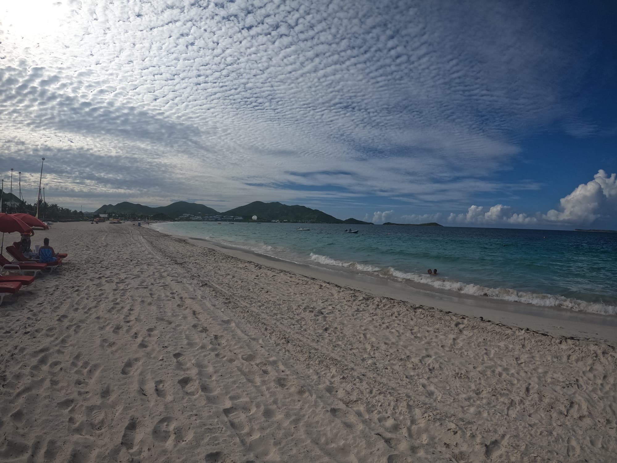White sand and calm water at Orient Bay with green hills behind