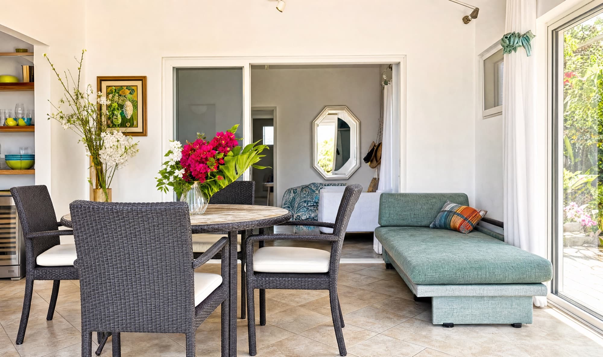 Rattan dining table and seafoam daybed with bougainvillea on the table