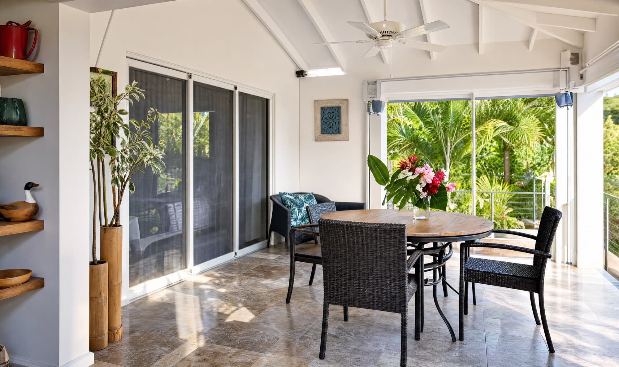 Dining corner under ceiling fans with palms filling the screened windows