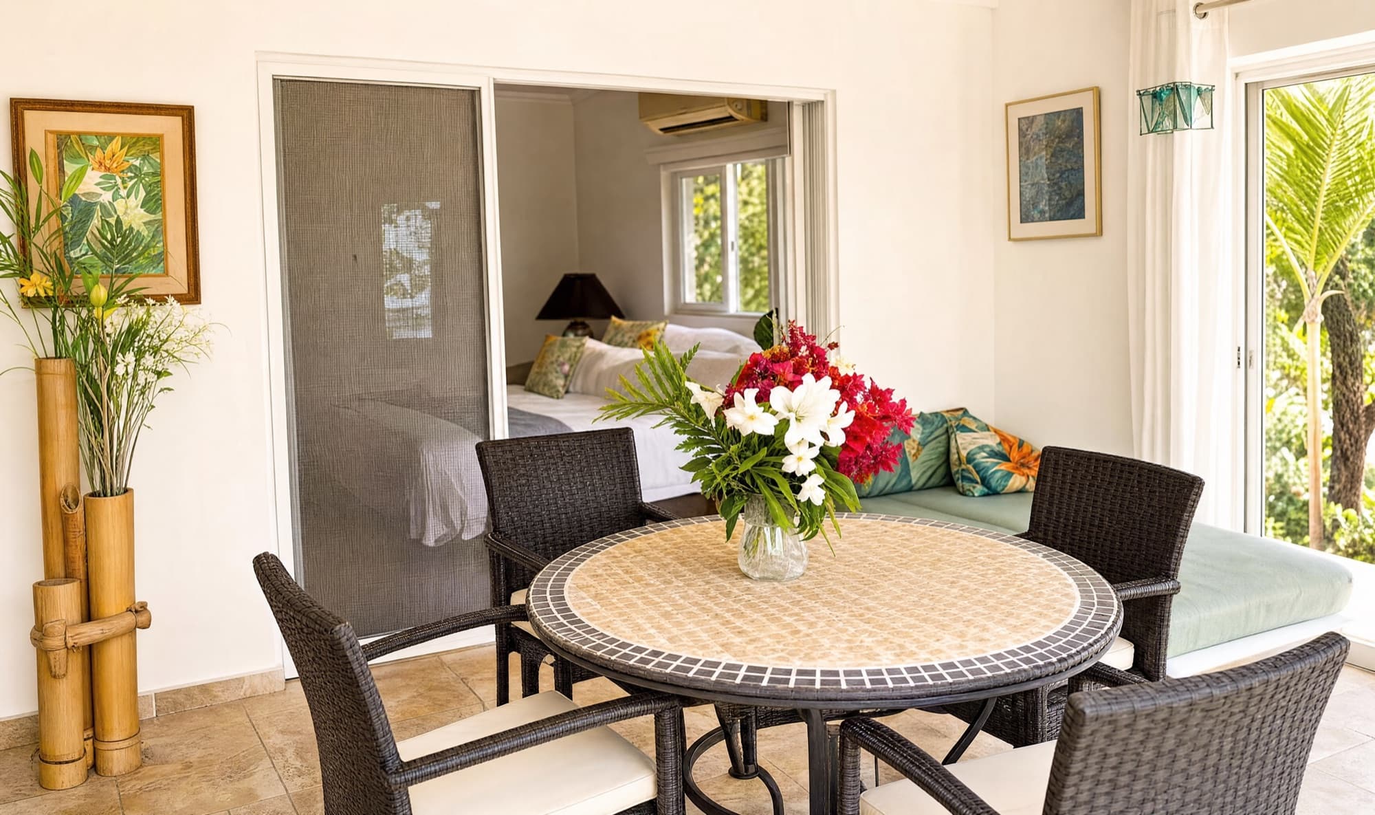 Round mosaic dining table with fresh flowers, opening to the bedroom suite