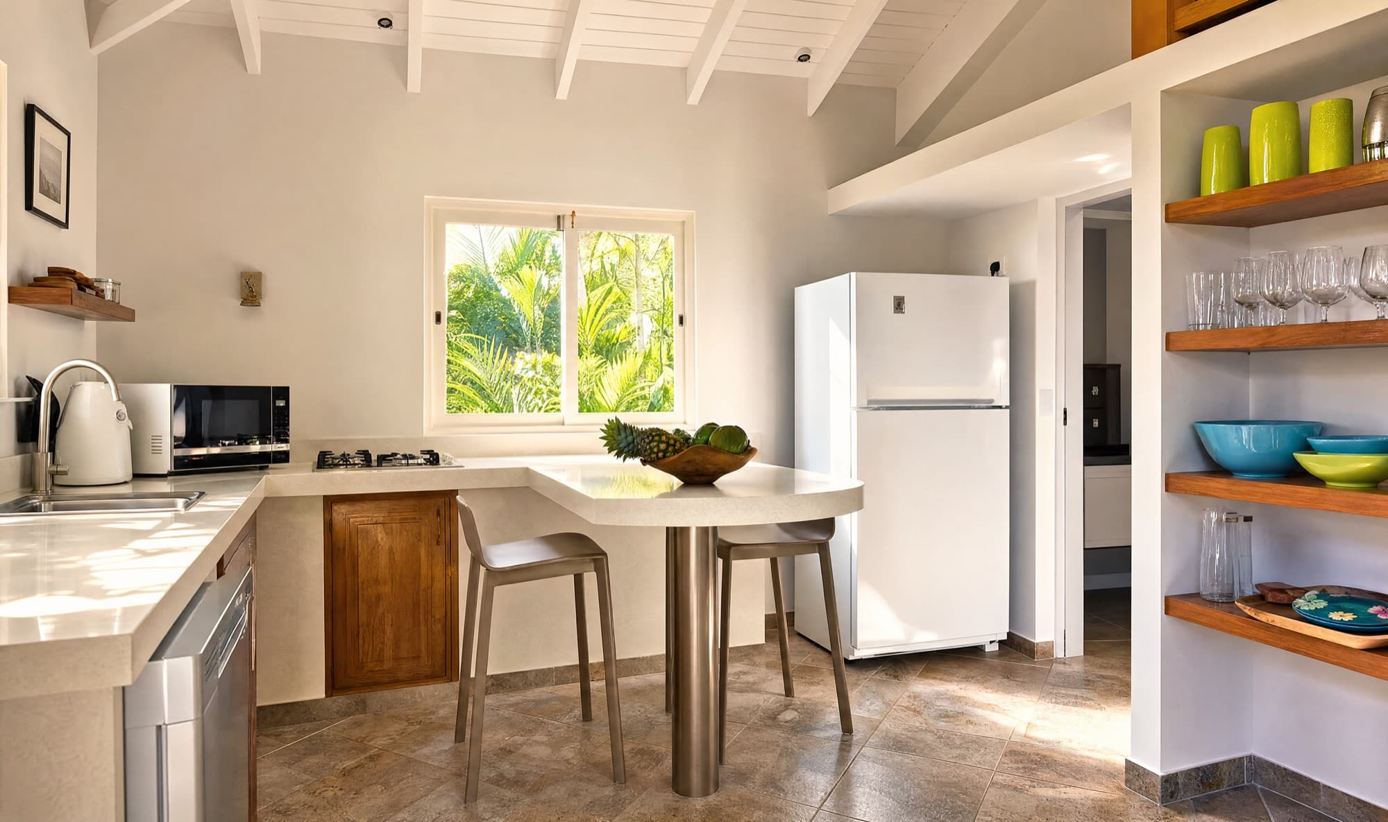 Kitchen breakfast bar with fruit bowl, gas hob and colourful open shelving