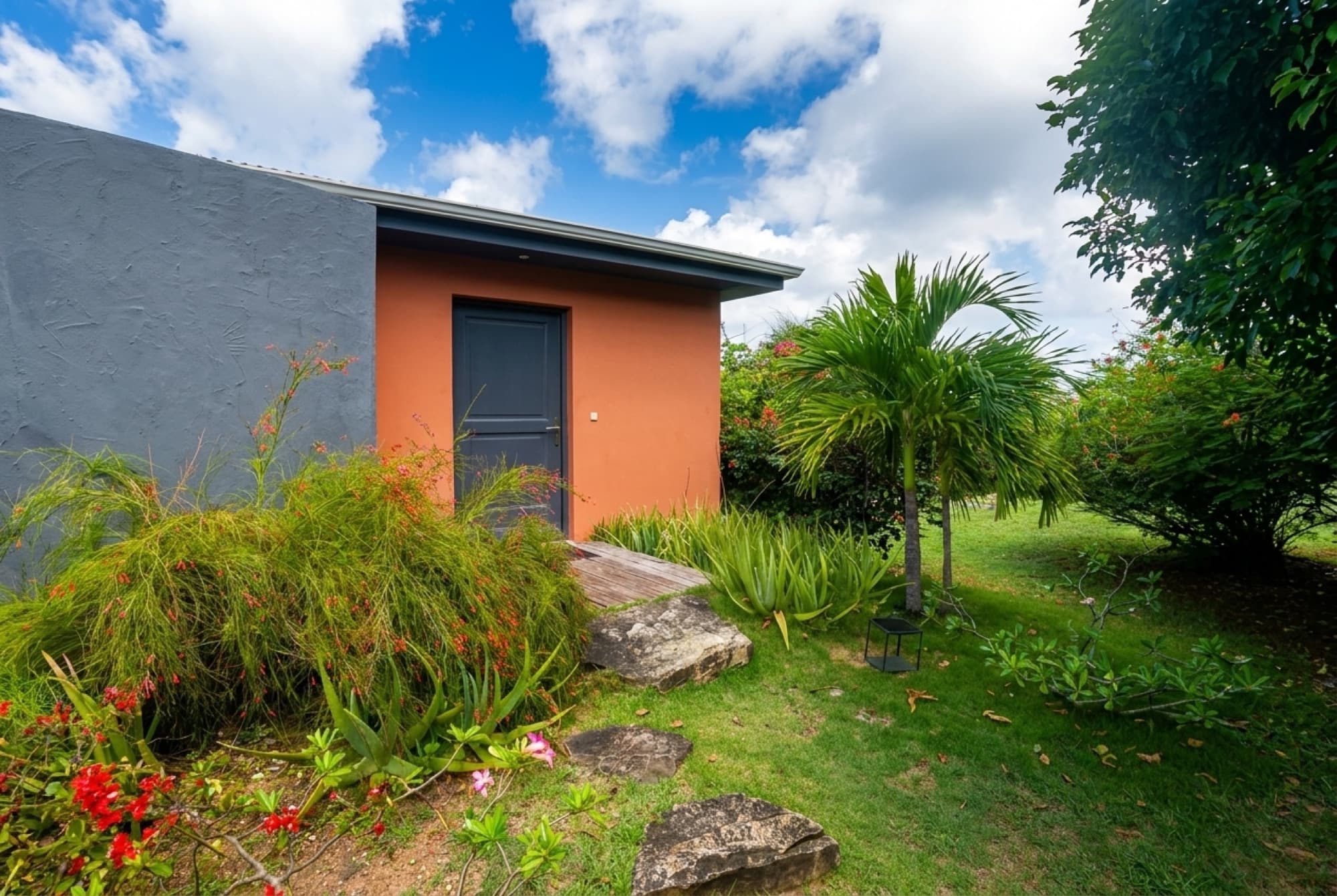 The guest house's private terracotta entrance amid palms and tropical planting