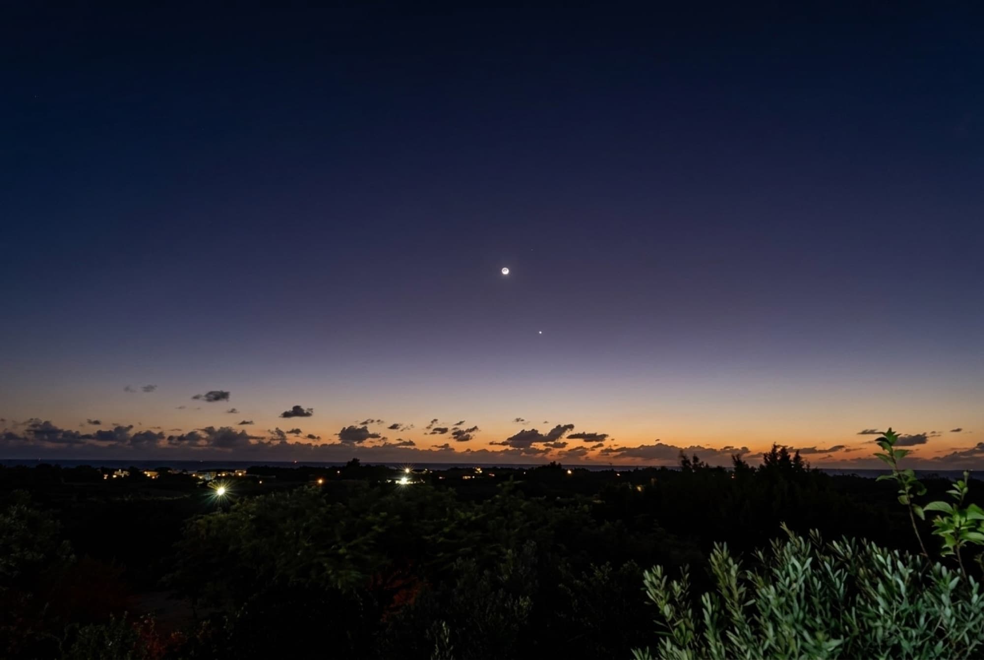 Venus shining in a deep indigo dusk sky over the twinkling island below