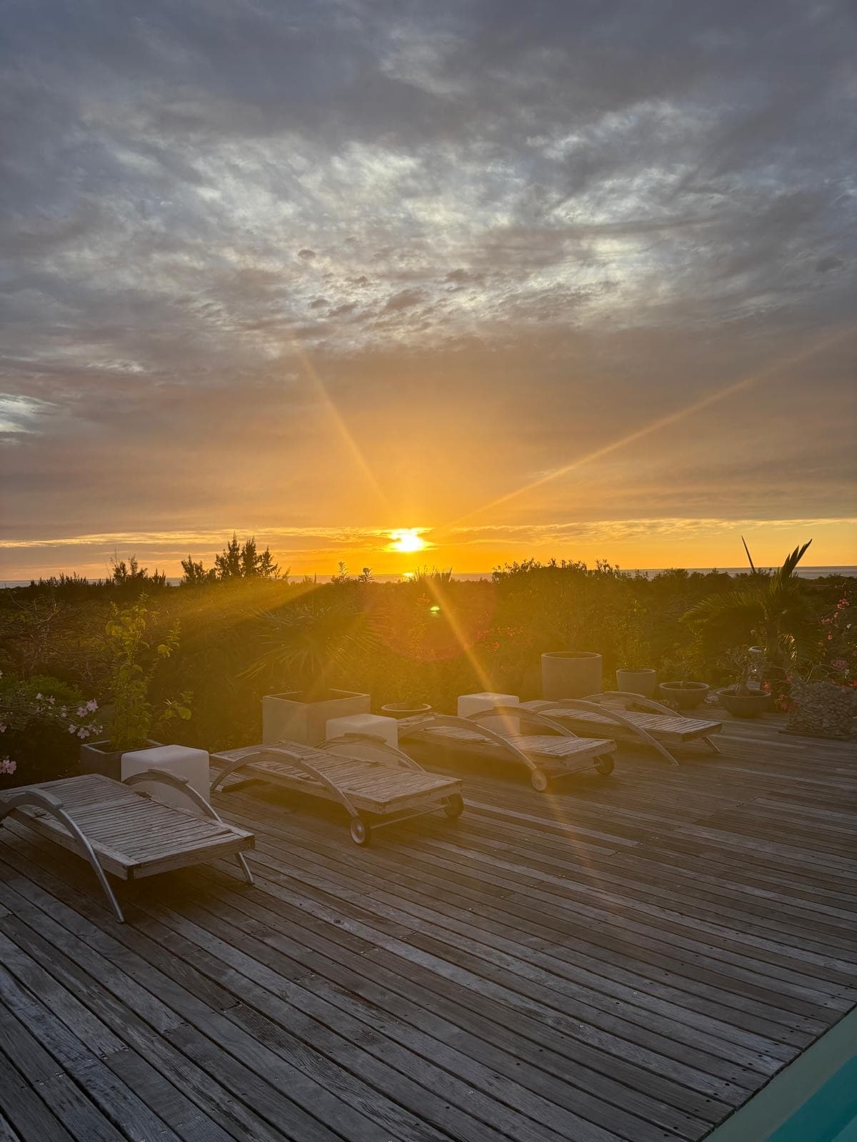 Sunbeams over lounge chairs on the estate terrace as the sun sets over the sea