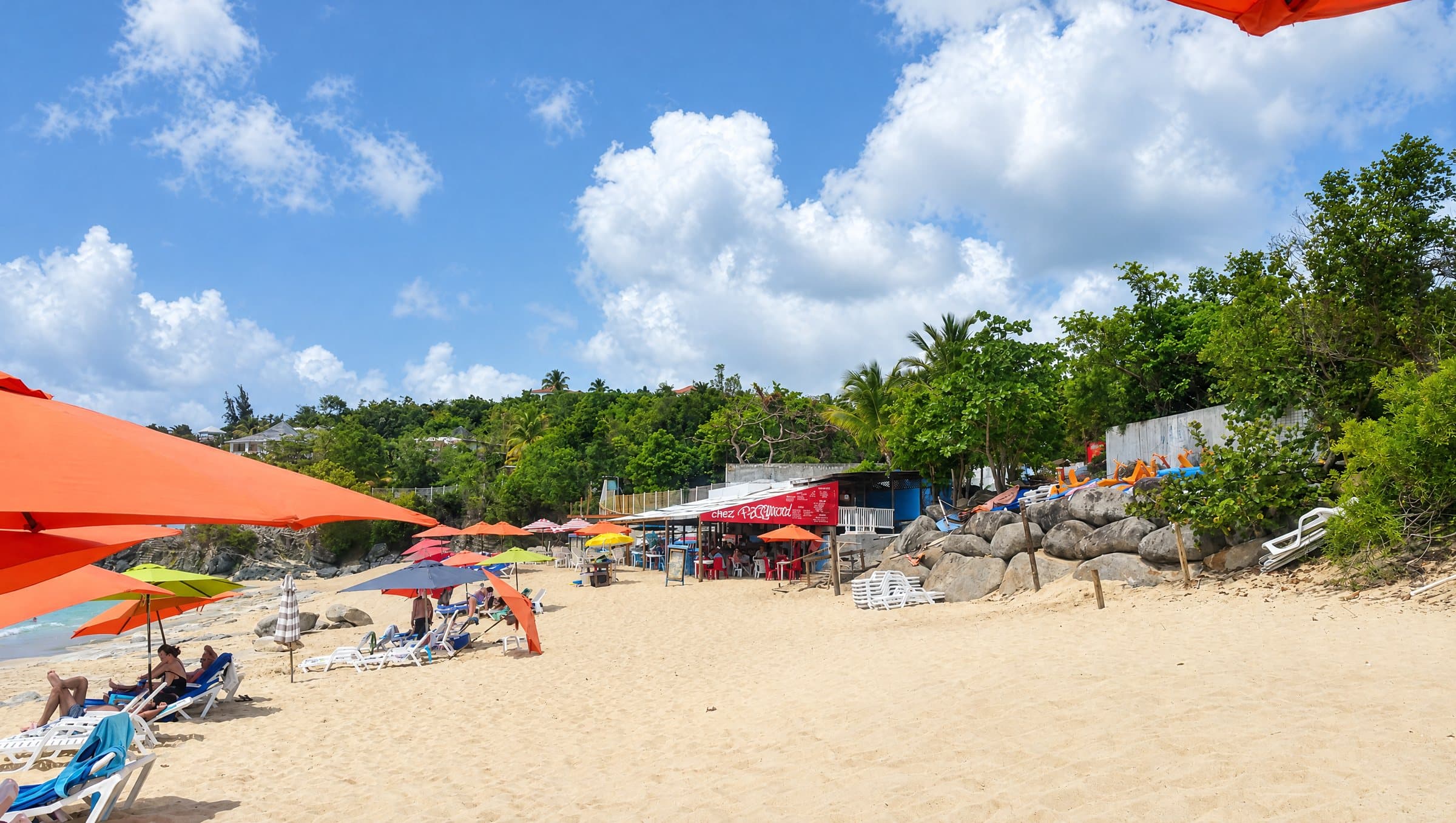 Baie Rouge en 2017, avec des parasols orange, des transats et le bar de plage rouge Chez Raymond sur le sable