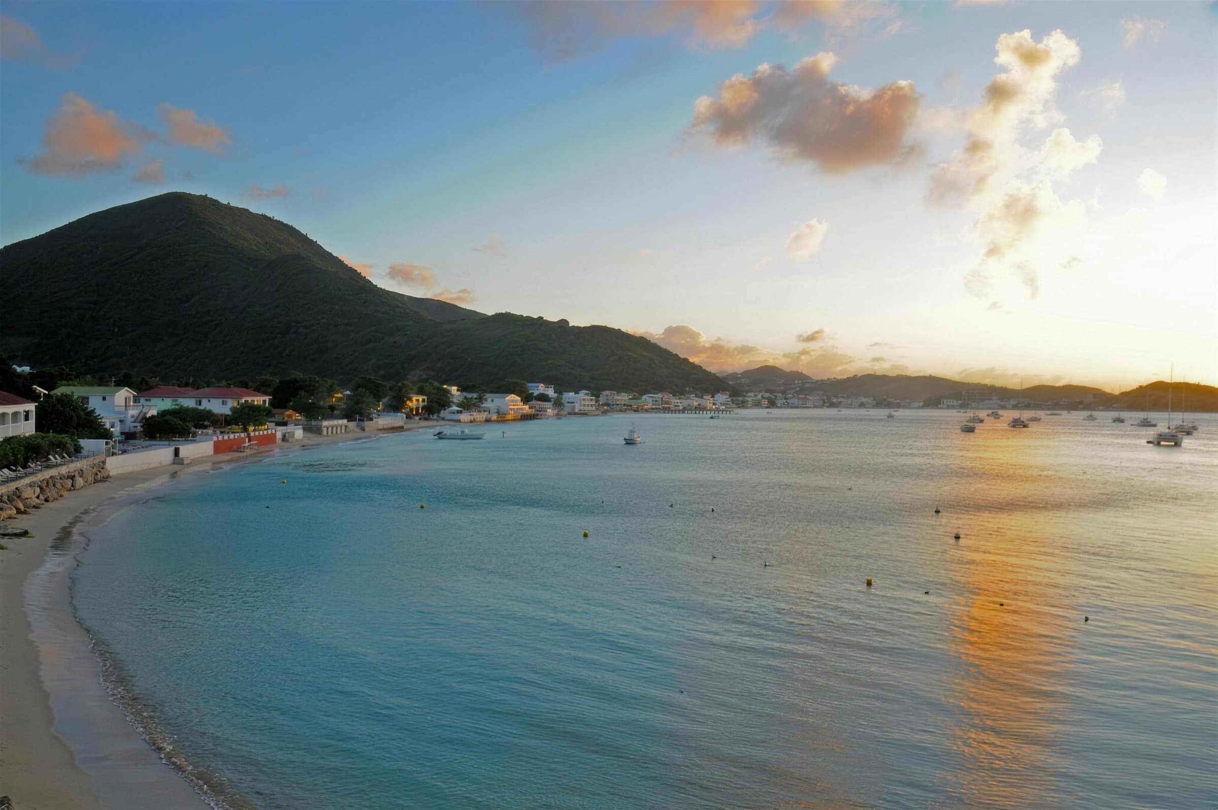 La baie de Grand Case dans la lumière du soir, avec le village le long du rivage et des bateaux au mouillage